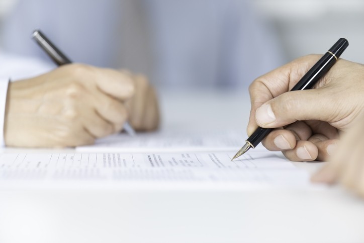 Signing agreement © simarik / GettyImages